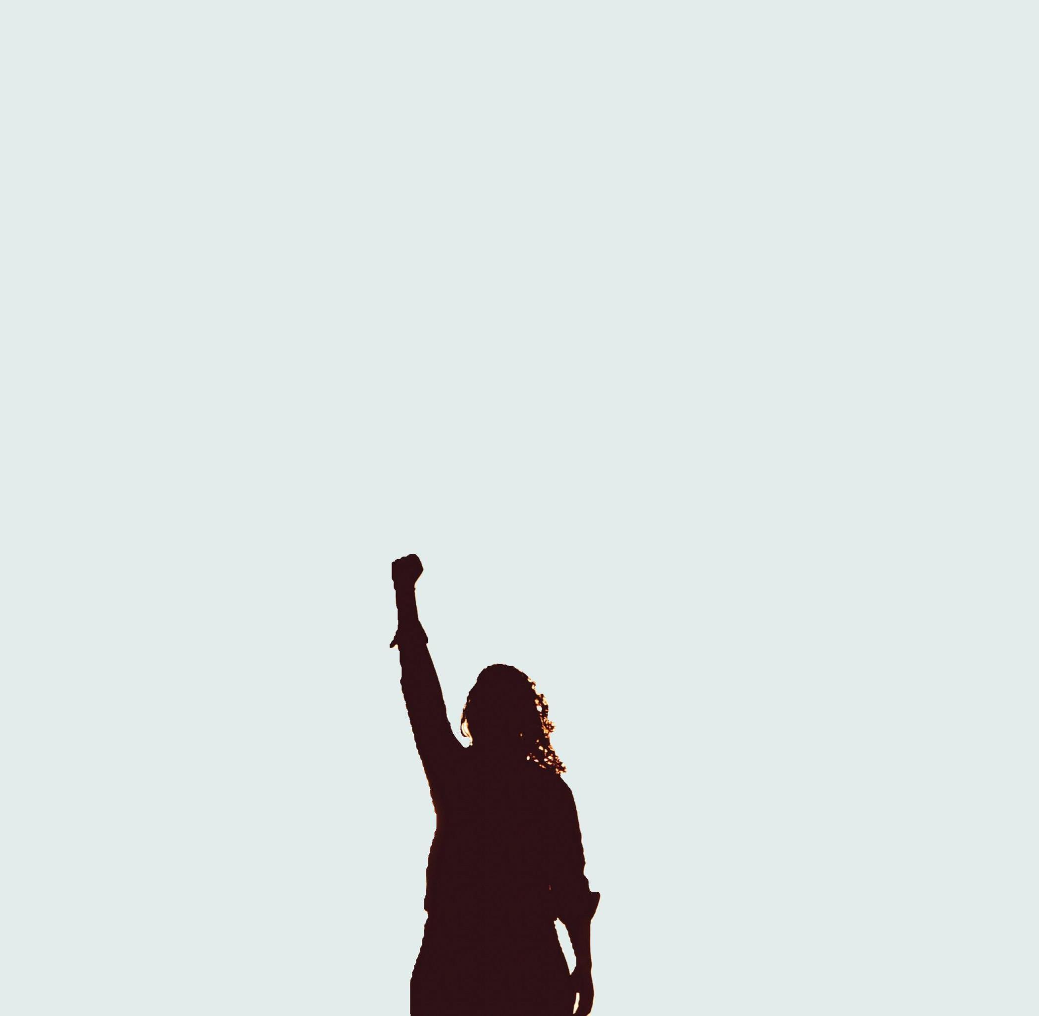 Silhouette einer Person mit erhobenem Arm vor hellem Hintergrund – ein kraftvolles Symbol für Empowerment und Ausdruck.