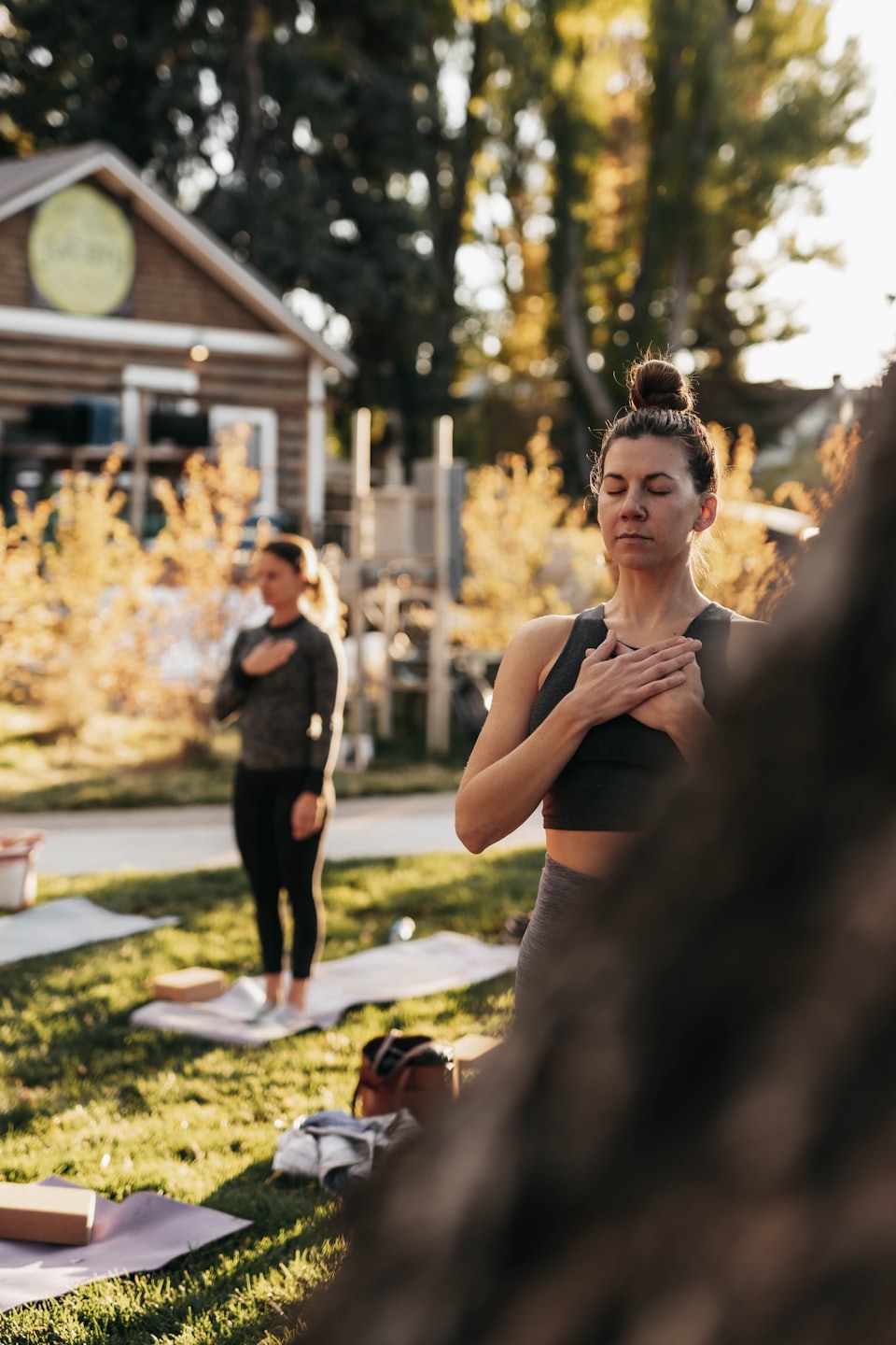 Person in achtsamer Haltung bei einer Outdoor-Meditation, mit geschlossenen Augen und Händen auf der Brust – ein Moment der Selbstverbundenheit und des Vertrauens in den eigenen Körper.